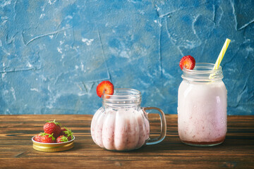 ripe strawberries in a lid from a can. in a glass fresh strawberry smoothie on a wooden table. blue background