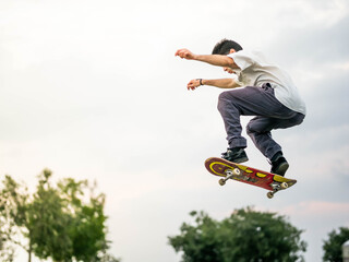 Young athletic male doing tricks with a skateboard at a skate park during daytime