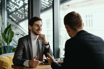 Focused businessman listening to business partner talking during discussion, thinking over his...