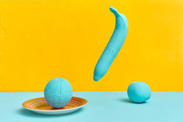 painted banana orange apple in turquoise color on a yellow background. creativity design concept