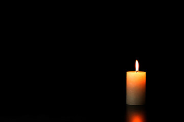one burning candle on a black background sorrow with copy space