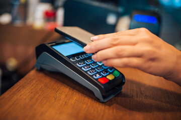 Woman making a contactless smartphone payment, close-up.