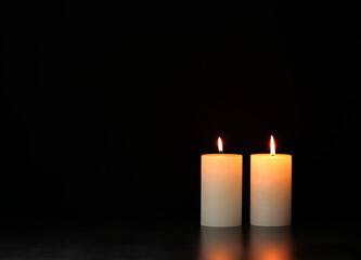two burning bold candles on black background 