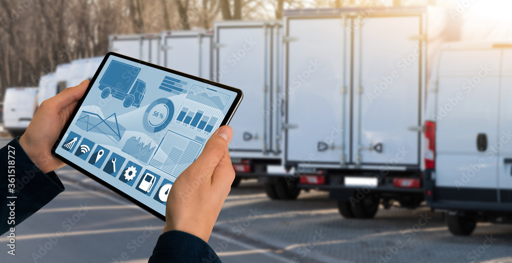 Poster manager with a digital tablet on the background of trucks. fleet management