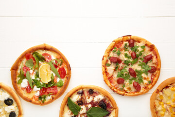 Variety of pizzas on white wooden background with copy space