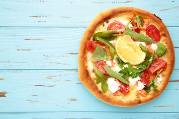 Margherita Italian pizza with cheese and tomato garnished with on blue wooden table with copy space