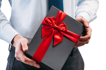 Business man holding a gift with a red ribbon. Guy on a white background in a light shirt with a tie. Black gift box in the hands..