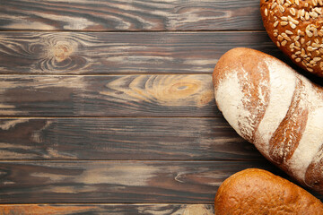 Fresh baked bread on brown wooden background with copy space.