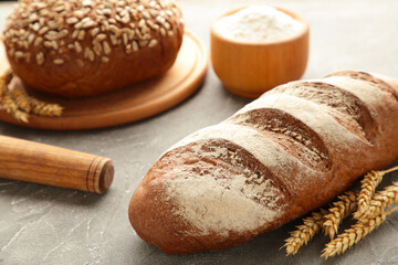 Delicious freshly baked brown bread on grey wooden background
