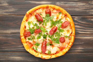 Tasty Italian pizza with sausage on brown wooden table