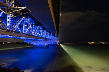Auckland Harbour Bridge at night with lights and reflection on water
