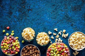 Colorful popcorn in bowl on blue table top-down copy space