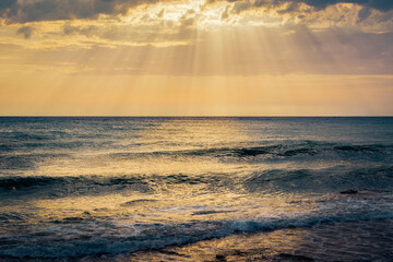 Calm sea waves hitting seashore. Beautiful summer day with sunrays shining through clouds. Endless horizon over the ocean