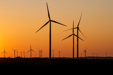 Black Silhouette of windturbines energy generator on amazing sunset at a wind farm in germany