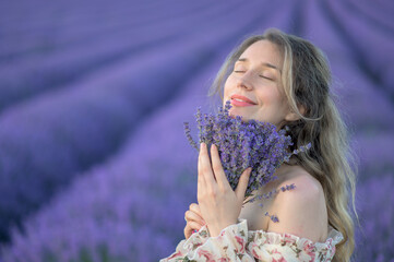 Woman smelling a lavender bouquet. Happy dreamy smile. Cute summer dress curly hairs