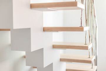 Elegance contemporary designed stairs in a white modern room of luxury apartment. No people, natural lighting.