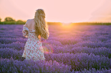 Happy woman dancing in a lavender field at sunset. Beautiful flower meadow. Summer sunset colorful...
