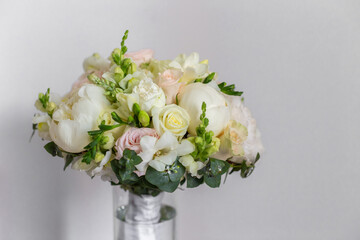 Wedding bouquet in a glass vase on the stairs near the wall.