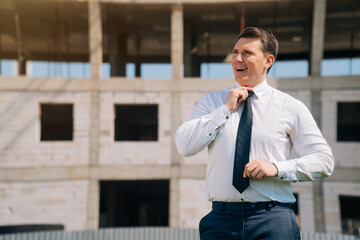 Elegant European man in business clothes against the background of construction.