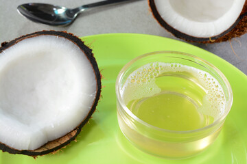 Isolated coconut oil in a cup with split coconuts