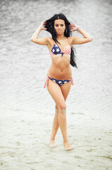 Obraz premium Woman on the beach in a swimsuit with an American flag having fun
