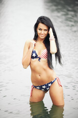Obraz premium Woman on the beach in a swimsuit with an American flag having fun