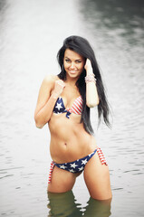 Obraz premium Woman on the beach in a swimsuit with an American flag having fun