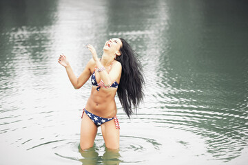 Woman on the beach in a swimsuit with an American flag having fun