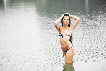 Woman on the beach in a bathing suit with an American flag having fun