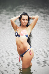 Fototapeta premium Woman on the beach in a bathing suit with an American flag having fun