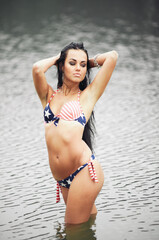 Obraz premium Woman on the beach in a bathing suit with an American flag having fun