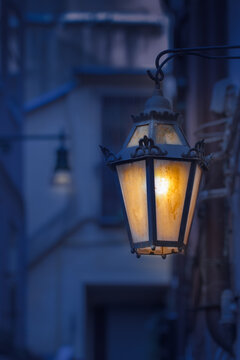 Glowing yellow vintage lantern on a cozy Italian street at night