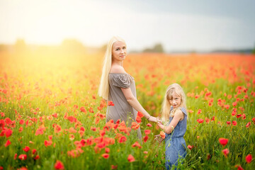 Happy family resting on a beautiful poppy field at sunset. family having fun.