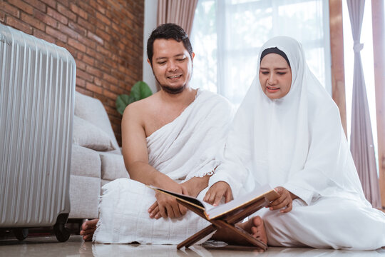 asian young couple praying with Al-Qur'an and prayer beads in white traditional clothes