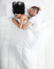 Top view of family couple sleeping together in bed. Man hugging woman under blanket. Peacefully...