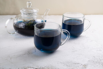 Blue Thai Anchan tea in two glass cups and a glass teapot. Beautiful indigo color. Copy space.