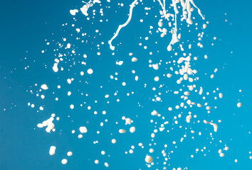 Splashes of white milk isolated on a blue background.