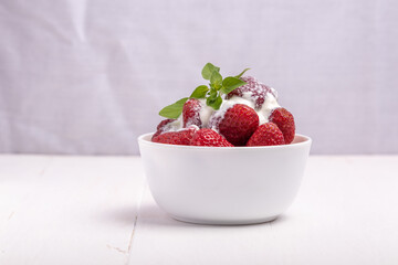 strawberries in a white bowl with leaves of lemon balm