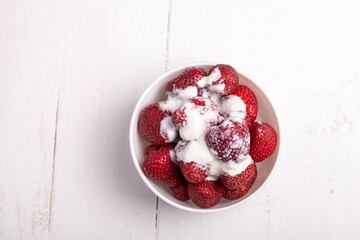 strawberries in a white bowl with ice cream on white background
