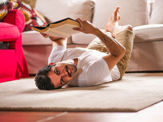 Fototapeta premium A picture of a brunette male laying on the ground and reading a book
