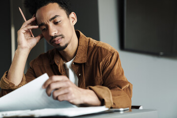 Photo of serious african american man thinking while working at table