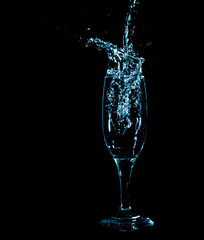 Splashes and drops of water in a glass are isolated on a black background.