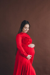 Fototapeta premium Pregnant woman in red flying dress holding her belly.