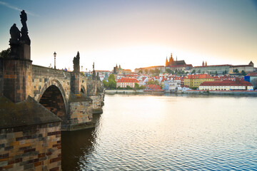 Fototapeta na wymiar Side view of Charles bridge and Prague castle over the Vltava river with sun setting in the background
