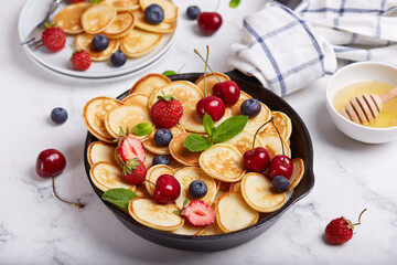 Mini pancakes with fresh berries and honey. Breakfast. 