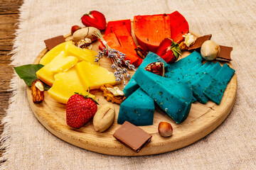 Cheese plate. Assorted multicolored hard Dutch cheeses. Blue and red pesto, aged gouda