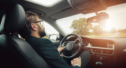 Rear view of businessman resting or sleeping on driver's seat staying in car on country roadside
