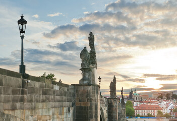 Fototapeta premium Side view of stone Charles bridge and its sculptures at sunset during lockdown