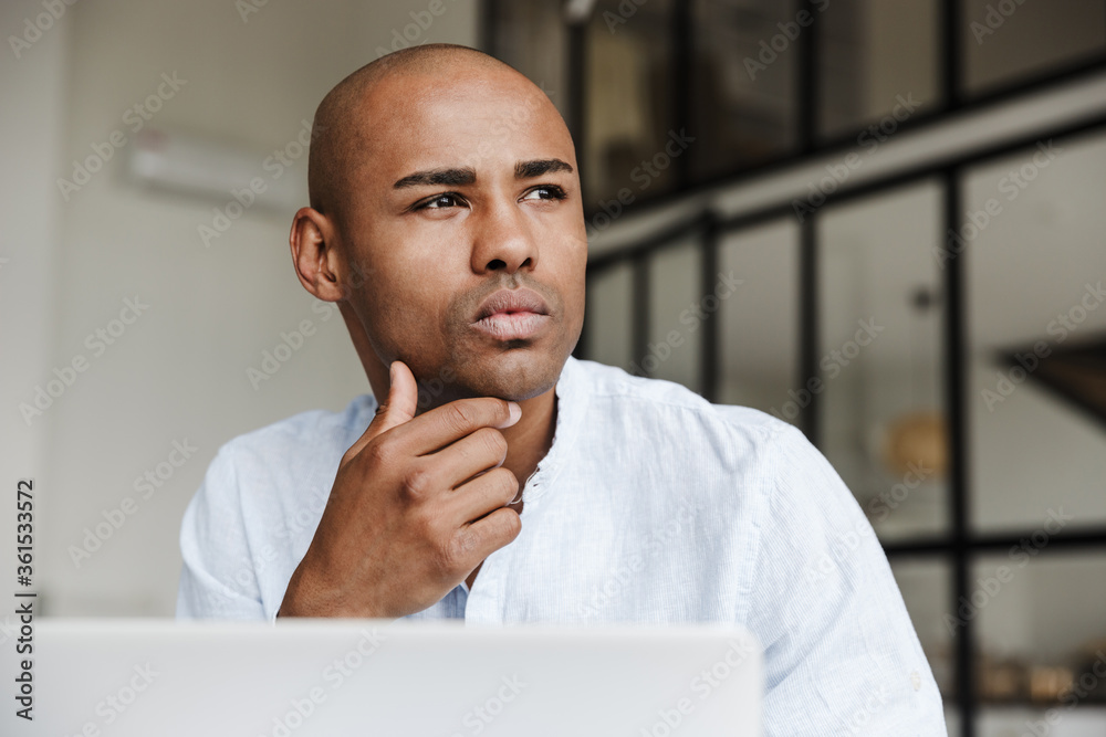 Wall mural photo of serious african american man working with laptop and thinking - Wall murals