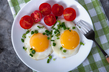 An appetizing breakfast with fried eggs, bread, cherry tomatoes and cheese. Fried eggs for breakfast. Sandwich with cheese and cherry tomatoes.